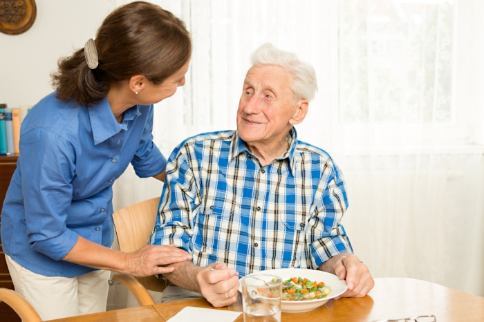 Woman caregiver assisting elder man.